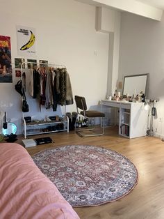 a bedroom with a bed, desk and hanging clothes on the wall next to it