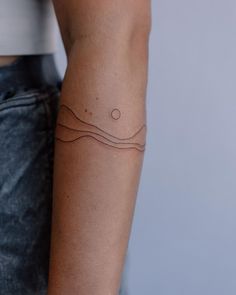 a woman's arm with a tattoo on it that has waves and dots in the middle