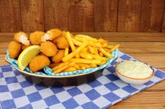 a bowl filled with fish and fries on top of a blue checkered table cloth