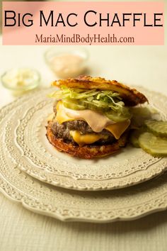 a hamburger with lettuce, cheese and pickles on it sitting on a plate