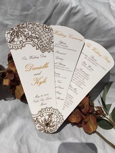 three white and gold wedding programs with flowers