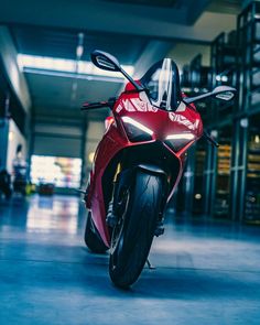 a red motorcycle parked in a garage with no one on it's back wheel