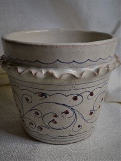 a white bowl with blue and red designs on it sitting on a cloth covered surface