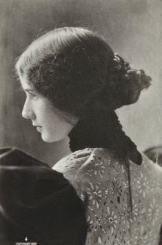 an old black and white photo of a woman with her hair in a pony tail