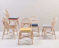 four chairs with different colored cushions and one chair has a seat cushion on the back