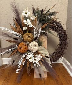 a wreath with flowers and feathers on top of a wooden floor