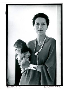 an old black and white photo of a woman holding a small dog in her arms