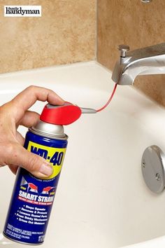 a person is cleaning a sink with a red spray