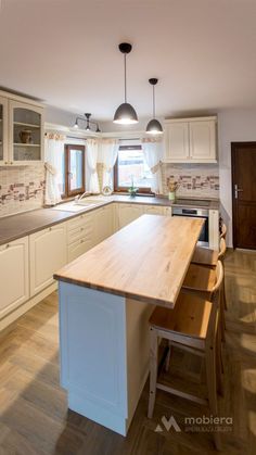 a kitchen with white cabinets and wooden counter tops, along with an island in the middle