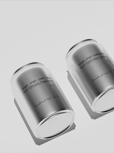 two silver cans sitting next to each other on top of a white surface with words written in them