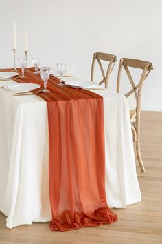 the table is set with white and orange linens