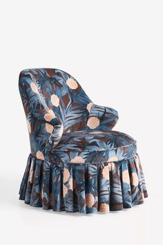 an upholstered chair with blue and pink flowers on the back, in front of a white background