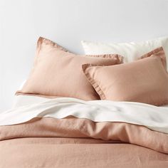 a bed with pink and white sheets and pillows