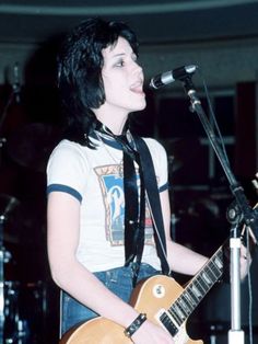 a woman singing into a microphone while holding a guitar