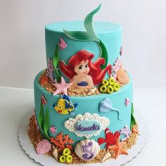 the little mermaid is sitting on top of this cake