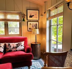 a living room with red couches and pictures on the wall next to it's windows