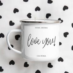 a white coffee mug with the words love you on it sitting in front of a black and white polka dot background