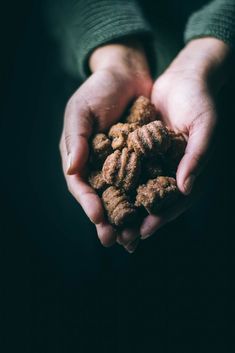 a person holding some food in their hands on a dark background with only one hand