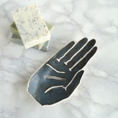 a hand shaped soap dish sitting on top of a marble counter next to a bar of soap