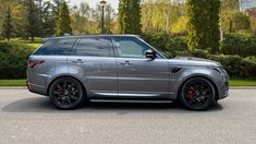 a grey range rover parked in front of some trees