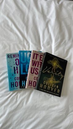 three books laying on top of a bed next to each other in front of a white sheet