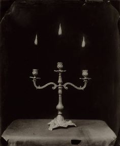 an old photo of a candelabra with candles on it in black and white