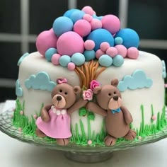 there is a cake decorated with two teddy bears on the top and balloons in the background