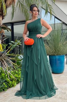 a woman in a green dress is holding an orange frisbee and posing for the camera