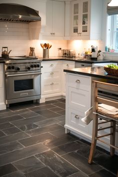 a kitchen with white cabinets and black counter tops, an island in front of the stove