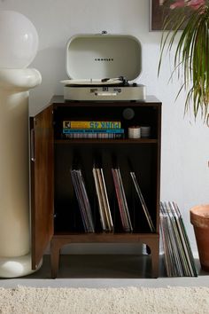 an old record player sitting on top of a shelf next to a potted plant