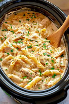 a crock pot filled with macaroni and cheese, chicken and parsley