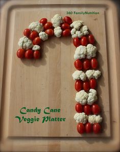 a wooden cutting board topped with cauliflower and cherry tomatoes in the shape of the letter f