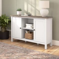 a living room with a white cabinet and potted plant on the floor next to it