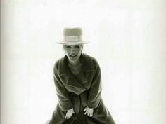 a woman in a coat and hat poses for the camera