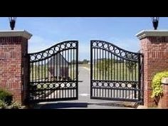 an iron gate in front of a brick building with two lamps on top of it