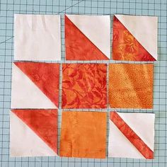 four blocks of orange and white quilts laid out on top of a cutting mat