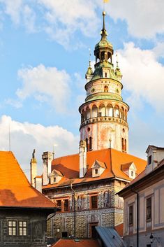 an old building with orange roof tiles and a steeple on top is surrounded by other buildings