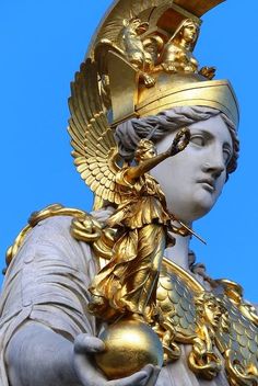 the statue is wearing a gold crown and holding an apple in his hand, against a blue sky