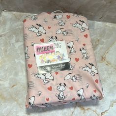 a pink blanket with snoopy dogs and hearts is on the floor in front of a tile wall