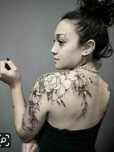 a woman with tattoos on her back holding a pen