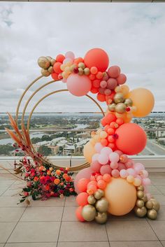 an arrangement of balloons and flowers on top of a building