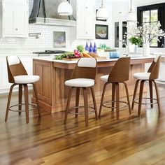 a kitchen island with four stools and an island in the middle is surrounded by white cabinets