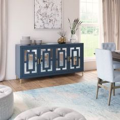 a dining room table with chairs and a blue cabinet in front of a large window