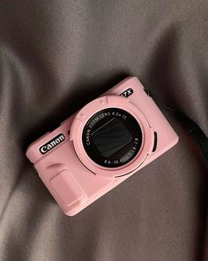 a pink camera sitting on top of a bed