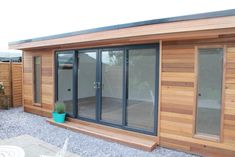 a wooden building with sliding glass doors on the front and side windows, in an outdoor patio area