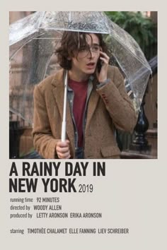 a young man holding an umbrella while talking on the cell phone in front of him