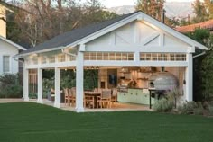 a white house with an outdoor kitchen and dining area