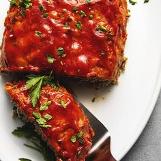 a white plate topped with meat covered in marinara sauce and garnished with parsley