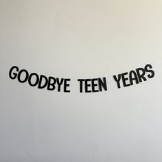 there is a sign that says goodbye teen years hanging on the wall in front of a white wall