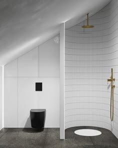 a black and white bathroom with a gold faucet in the shower head, toilet seat on the floor